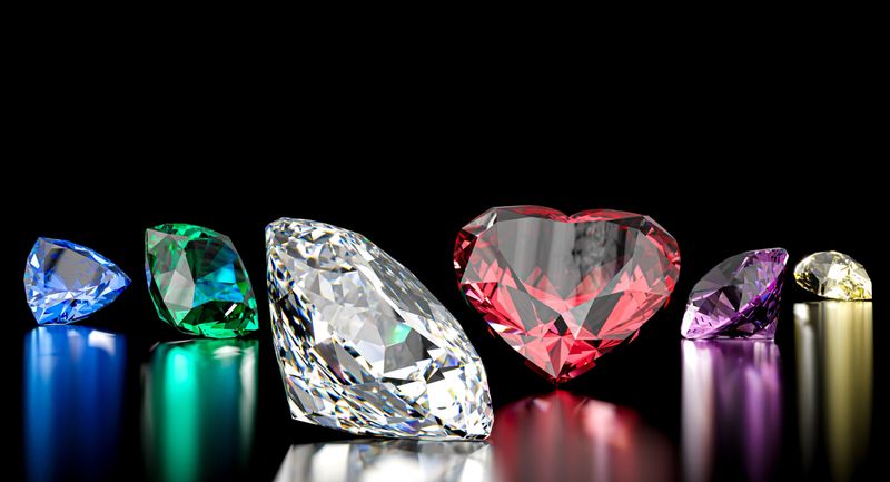 Colorful gemstones variety including red heart diamond on black surface