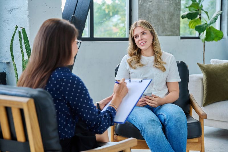 Smiling young woman at session with psychologist therapist. Happy female patient with psychotherapist counselor social worker. Mental psychological services, individual therapy help treatment support
