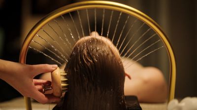 Person washing hair with brush under water.