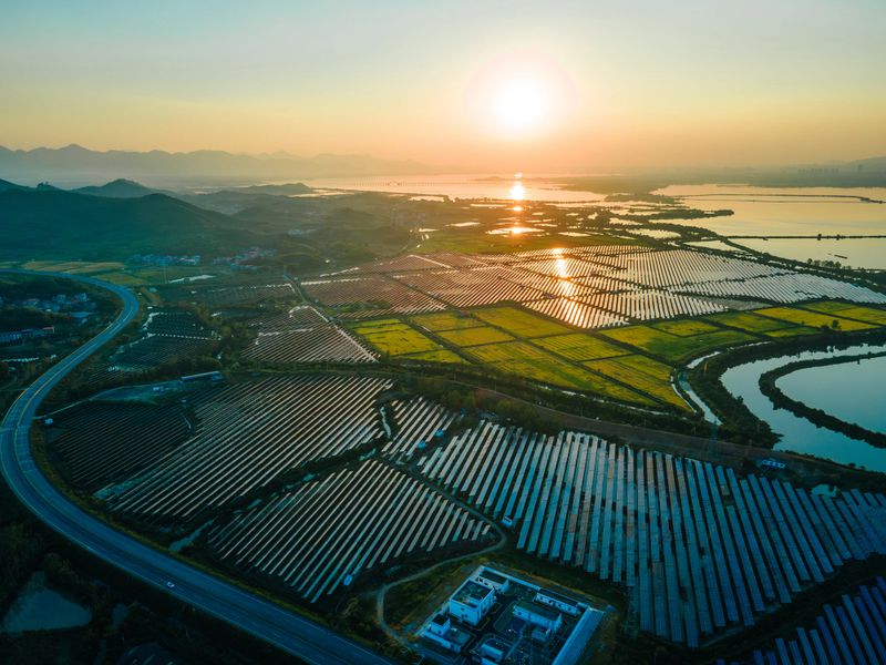 Sunset view of solar panels generating electricity, photovoltaic farm reflecting sunlight with warm orange glow, emphasizing sustainable energy and renewable power solutions.