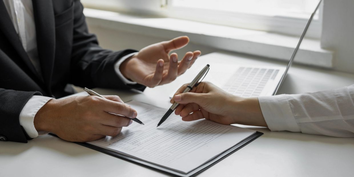 Two people discussing documents with pens.