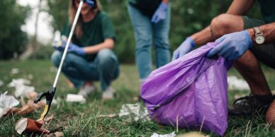 People cleaning up trash outdoors with gloves and bags.