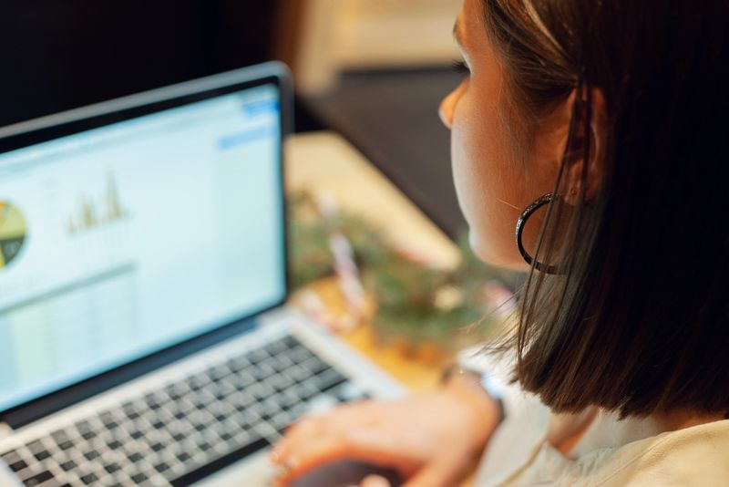 Close-up a confident business woman professional Analyzing Data while working on a laptop, viewing graphs and charts on the screen. Great for finance, analytics, and business themes in a modern office