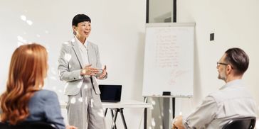 A professional woman presenting to colleagues in a modern office.