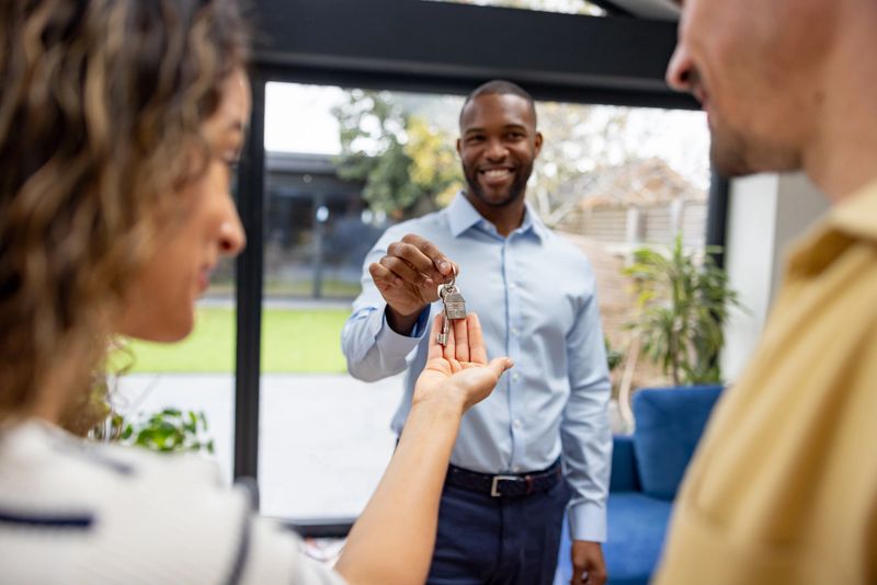 Real estate agent giving the keys of their new house to a happy couple - home ownership concepts