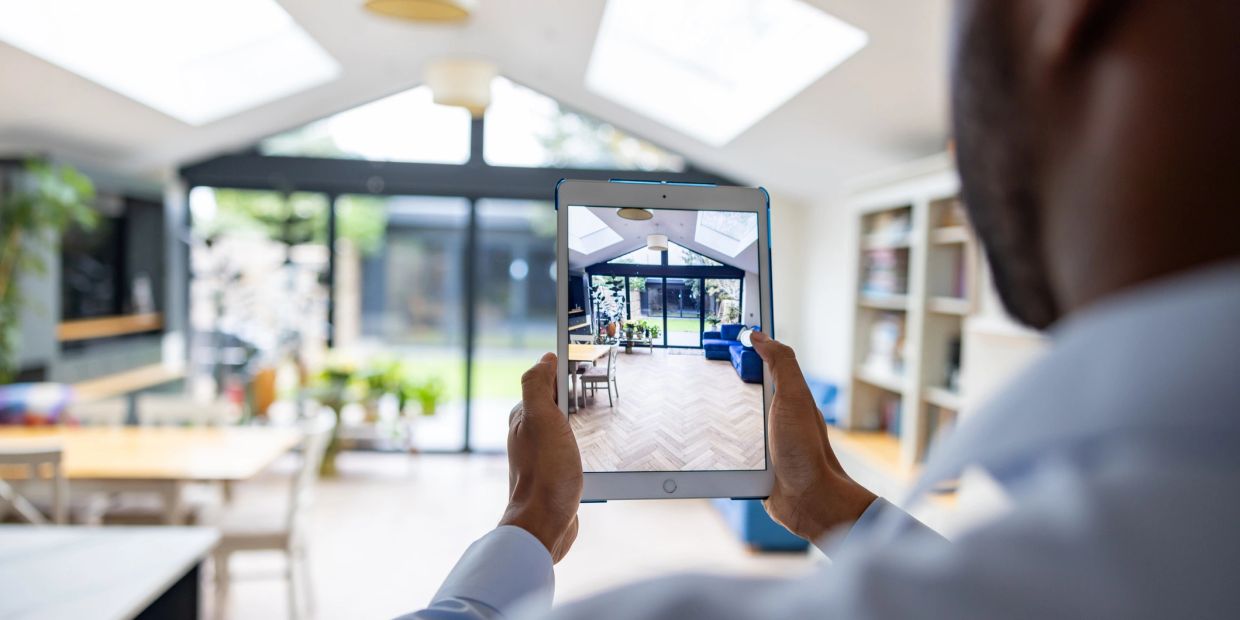 Person holding a tablet showing a room interior.