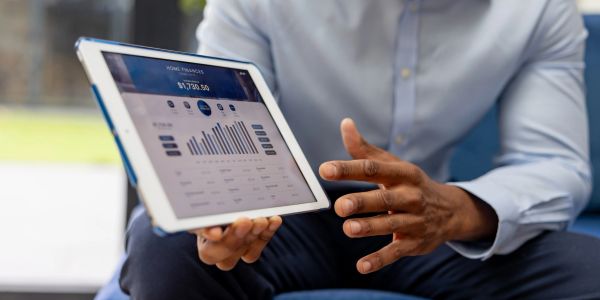 Person showing financial graphs and data on a tablet screen.