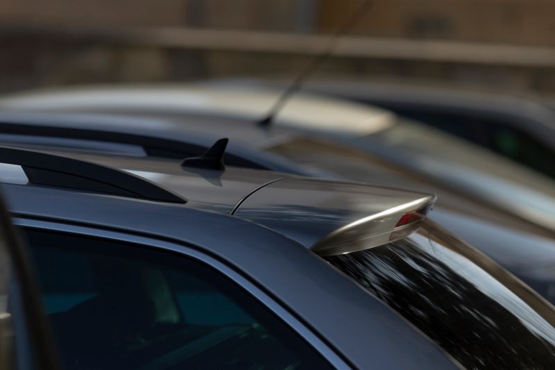 car design details, closeup of car rear styling, closeup highlighting aerodynamic lines and paint texture features, focused shot of modern compact car showing aerodynamic design and urban background