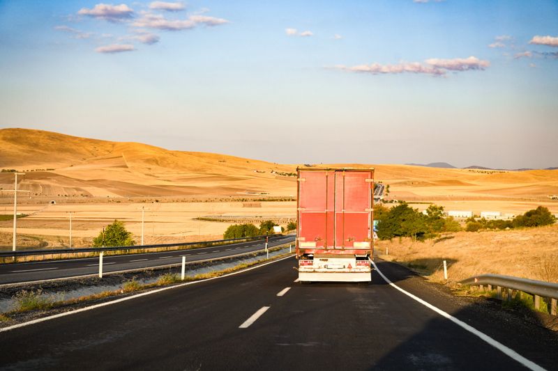 A truck transporting cargo in a dry cargo semi-trailer moves along the highway along the mountains