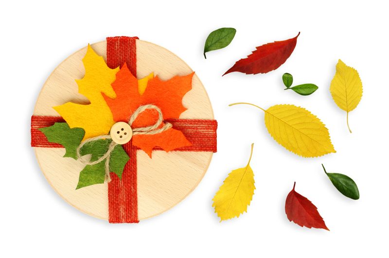 Beautiful gift box decorated with colorful autumn leaves, isolated on a transparent background. Seasonal fall composition symbolizing warmth, coziness, and festive mood