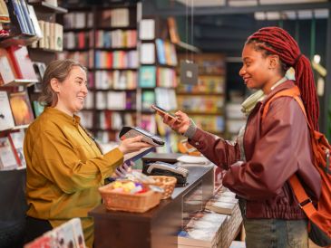 Customer using phone to pay a cashier in a bookstore.
