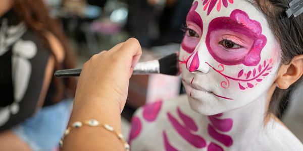 Child receiving colorful face painting.