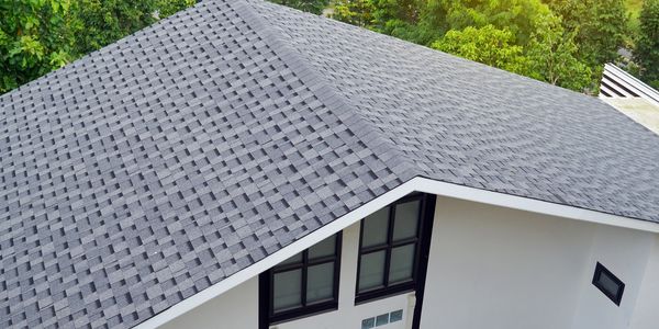 A house with a dark gray shingle roof and white walls.