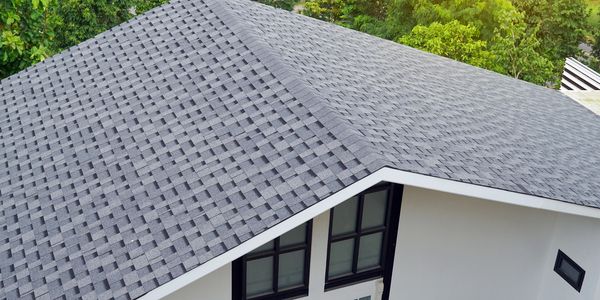 A house with a grey shingle roof and white walls.