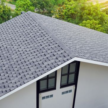 Gray shingle roof on a modern house surrounded by greenery.