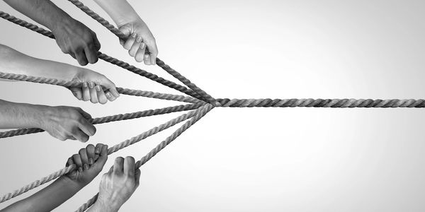 Multiple hands pulling ropes in a tug of war.