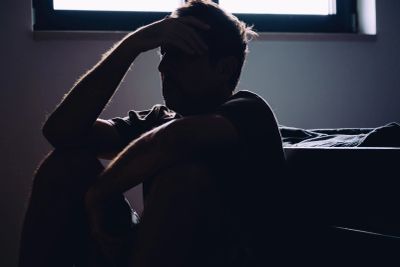 Silhouette of a person sitting with head in hand by a window.