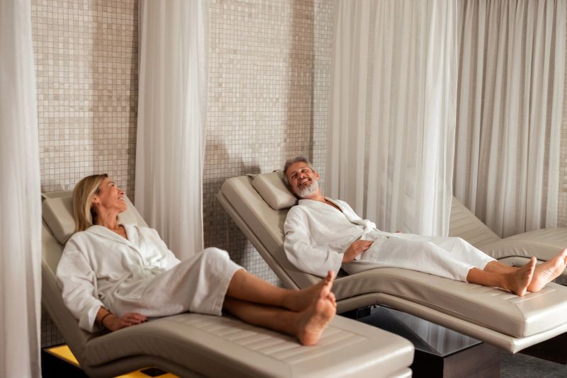 Caucasian couple bonding and resting on lounge chairs while taking a break at a luxurious spa