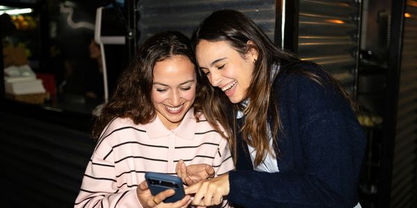 Two women happily looking at a phone.
