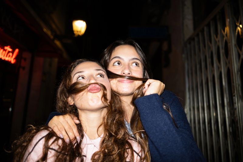Young women friends making mustaches with hair