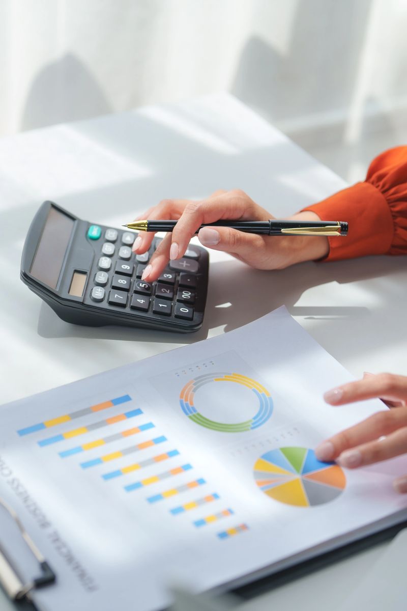Businesswoman analyzing financial charts, using calculator and pen, working with statistics document