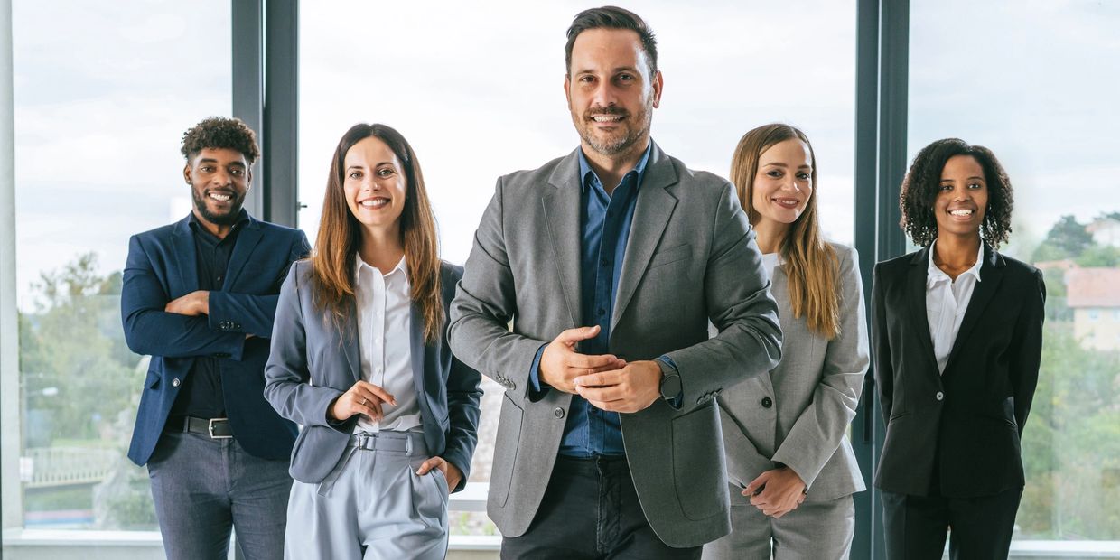 Confident diverse business team standing in modern office, smiling.