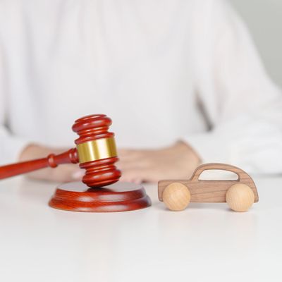 A judge's gavel next to a small wooden toy car on a white table.