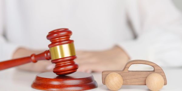 Judge's gavel beside a wooden toy car on a white table.