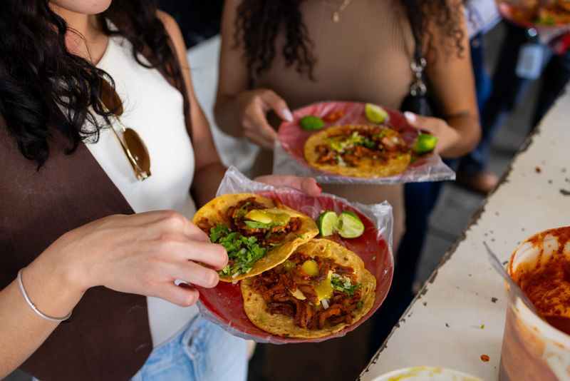 Two friends, getting to know Mexico, stop to eat tacos al pastor on the street.