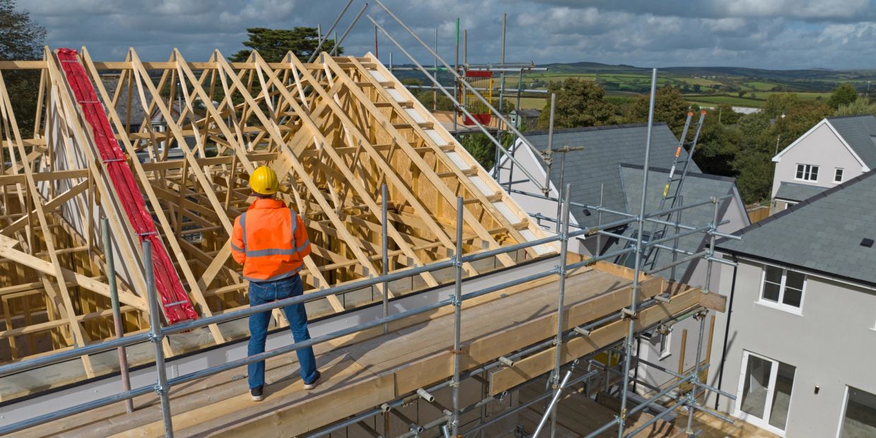 Construction worker inspecting wooden roof framing.