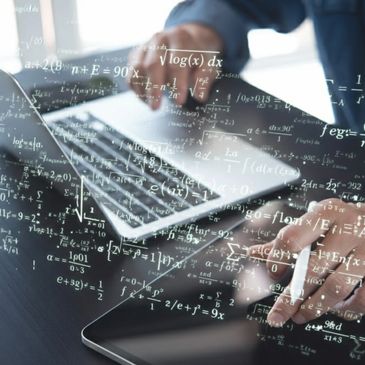 Person working on laptop and tablet with floating mathematical equations.