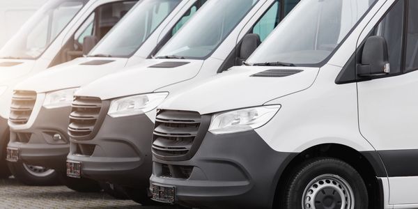 Row of white delivery vans parked side by side.