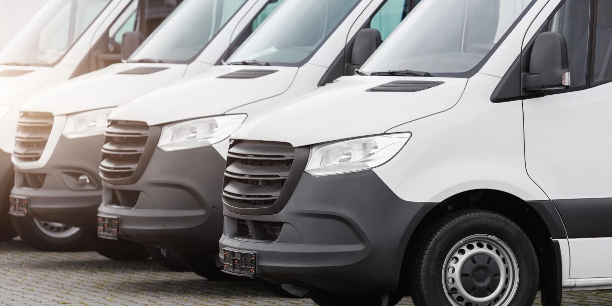 Line of white delivery vans parked together.