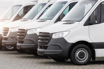 Row of white commercial vans parked in a line.