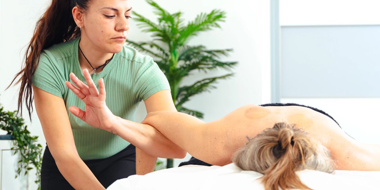 Therapist performing a shoulder stretch on a client lying on a massage table.