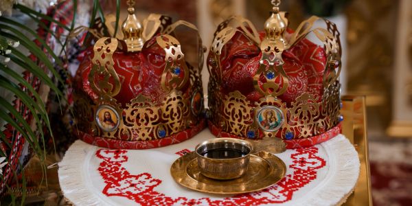 Two ornate crowns on an embroidered cloth with a chalice and plate.