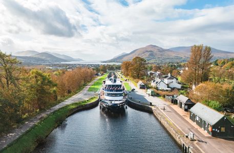 Boat passing through a canal lock in a scenic autumn landscape.