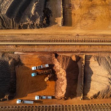 Aerial view of construction site with trucks and railway tracks.