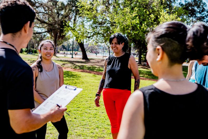 Mature trainer talking to athletes on public park