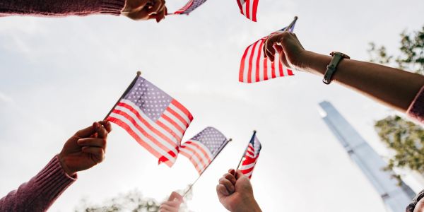 People waving small American flags against a bright sky.