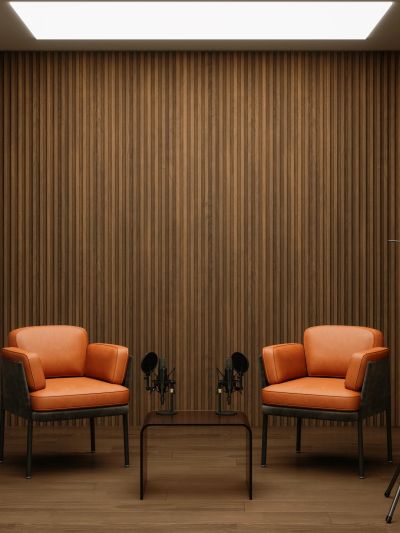 Two orange armchairs with microphones in a wooden-paneled room.
