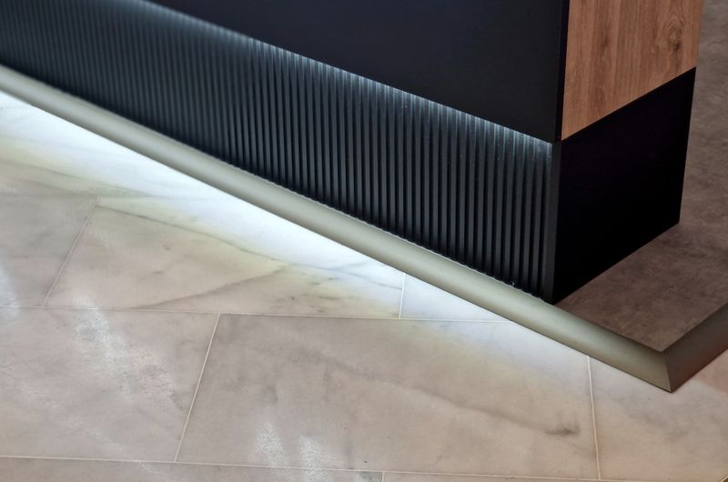 Grooved design of wooden planks of triangular profile on the wall of the store. Laminate with stone text in triangle surface stripes on the kitchen counter cladding