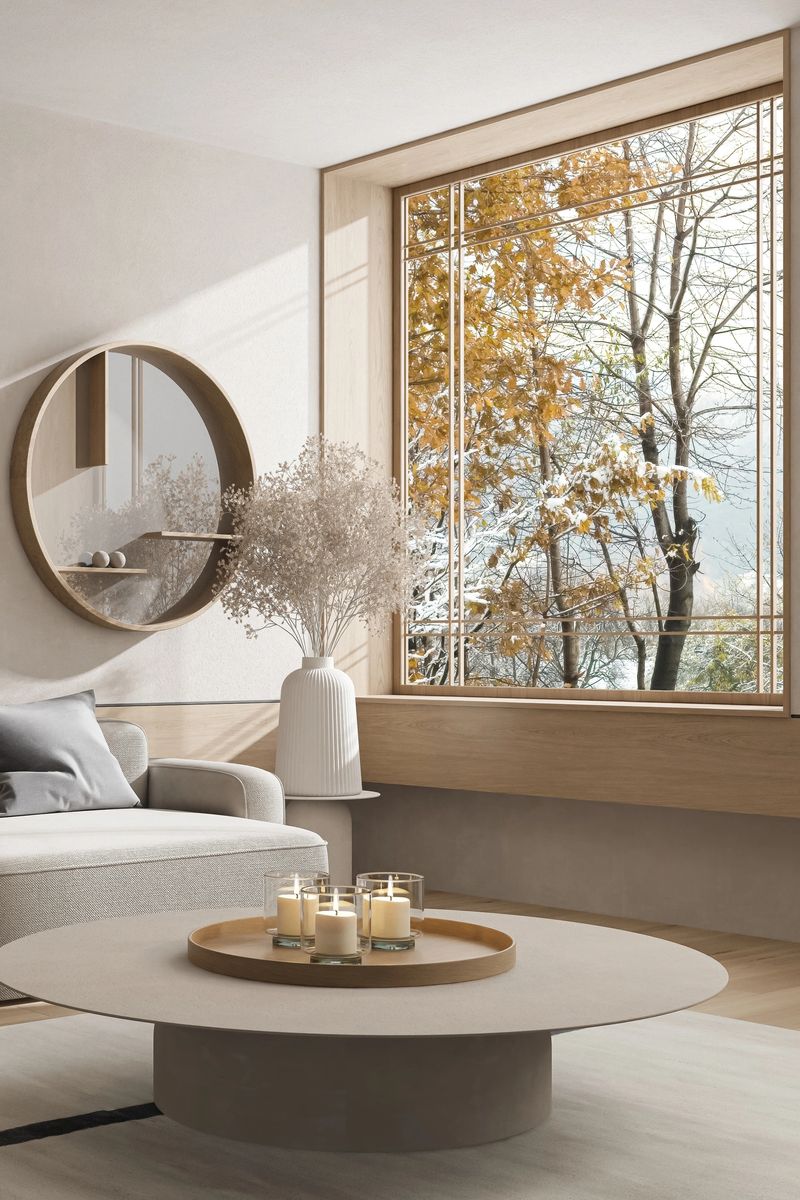 A Japandi modern style living space that blends minimalist Japanese design with Scandinavian warmth, illuminated by soft natural daylight and sun rays. The interior features a refined mix of concrete, stone, pine wood, and neutral textiles, arranged with clean lines and organic balance. Circular forms, textured surfaces, and curated decorative elements contribute to a serene and functional aesthetic. Hidden LED accents complement the sunlight, enhancing architectural details without overpowering the calm atmosphere. This image is ideal for illustrating modern interior design, lifestyle features on simple living, or visual content focused on wellness, natural materials, and daylight-optimized home environments.