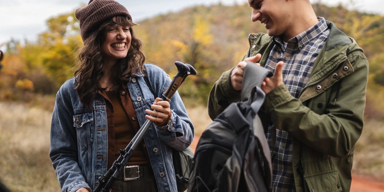 Two friends preparing for a hiking adventure outdoors in autumn.