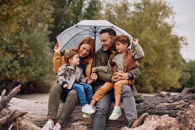 Family sitting together under an umbrella outdoors