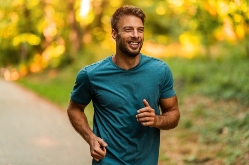 Happy young athletic man running in nature.