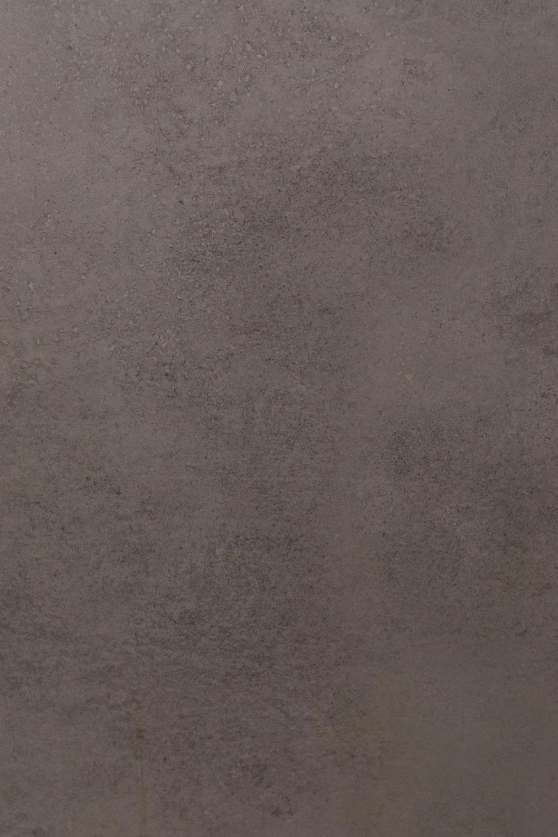 A textured surface displays varying shades of gray, with slight patterns visible. Soft afternoon light reveals the intricate details of the surface, creating a calming effect.