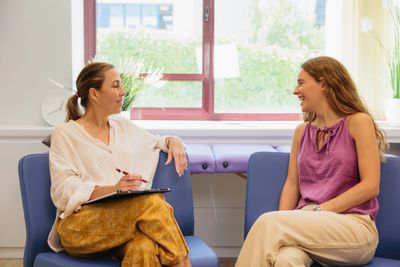 Two women engaged in a friendly conversation in a bright room.