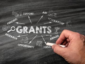 Hand writing grant-related terms on a chalkboard.