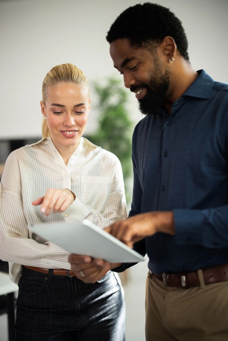 Diverse coworkers reviewing data on a tablet, discussing business ideas in an office